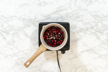 Simmering fresh cranberries to make a flavorful sauce for the cranberry buttercream topping.の写真素材