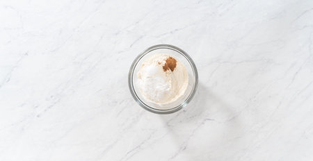 Flat lay. Mixing dry ingredients with a hand whisk in a glass mixing bowl to prepare eggnog...