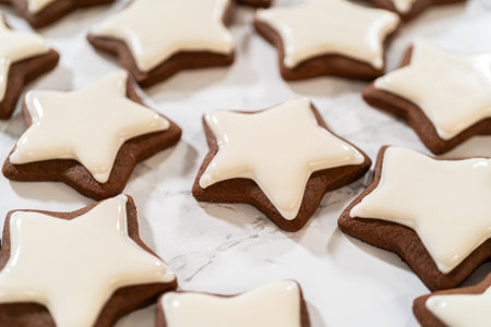 A neat arrangement of gingerbread star cookies covered in white royal icing, emphasizing their...