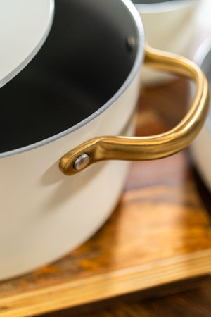 Top-down angle of a ceramic pot showing a curved gold side handle and soft light reflections on the matte surface.の写真素材