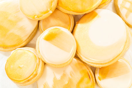 A collection of sugar cookies decorated with smooth royal icing and hand-painted gold accents. These...