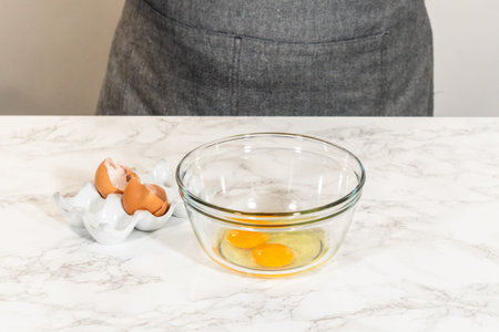 Front view of a small glass bowl with eggs, placed on a marble countertop.