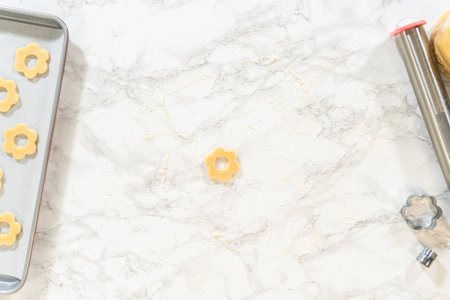 Single flower cookie dough with center cut placed on a floured marble counter. A part of the Easter Cookie Sandwich with Raspberry Buttercream recipe.の写真素材