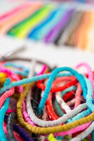 A vibrant collection of clay beads, neatly arranged by color on a white table, ready to inspire young crafters to create their own unique bracelets.の写真素材