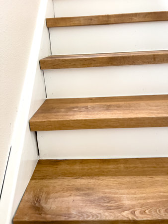 Interior staircase with light brown wooden treads and bright white risers. The clean and minimal...
