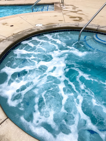 A view of a spa pool with water bubbling from active jets. The circular design, tile accents, and...