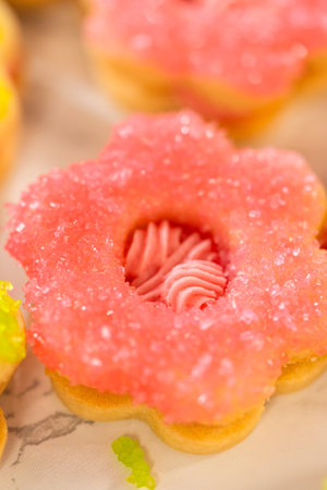 Single flower-shaped Easter Cookie Sandwich with vibrant pink sugar coating and Raspberry Buttercream, presented on a white marble surface. A close-up perfect for food features.の写真素材