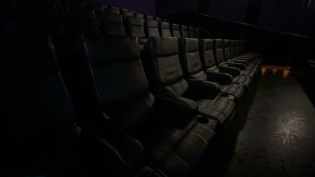 Parker, Colorado, USA-June 20, 2024 - A row of modern reclining theater seats is seen in a darkened cinema. The seats are unoccupied and illuminated only by faint overhead lighting. The mood is quiet and ambient.のeditorial素材