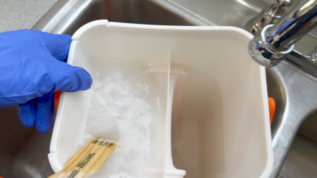 Parker, Colorado, USA-January 11, 2025 - A gloved hand is seen filling a bucket with water in a kitchen sink in Broomfield, Colorado. The image shows cleaning preparation during a home project.のeditorial素材