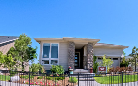 Parker, Colorado, USA-June 18, 2025 - A contemporary single-story model home is surrounded by well-maintained landscaping and a small black metal fence. The sky is bright and blue, highlighting the fresh architectural design.のeditorial素材