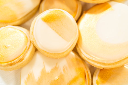 A collection of sugar cookies decorated with smooth royal icing and hand-painted gold accents. These elegant cookies are perfect for weddings, parties, and festive celebrations, adding a touch of luxury to any dessert table.の写真素材