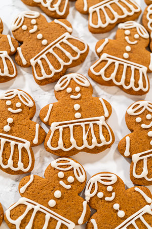 A large batch of gingerbread girl cookies featuring uniform royal icing designs, arranged to...