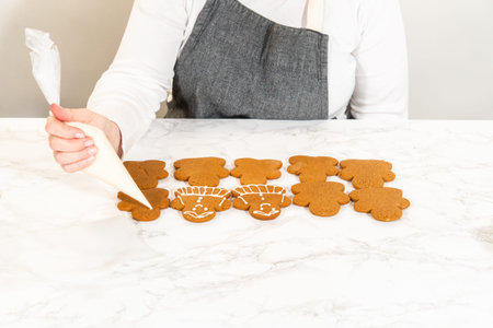 A neat arrangement of gingerbread girl cookies, fully decorated with white royal icing, placed in...