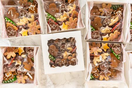 A collection of holiday-themed gift boxes filled with beautifully decorated Christmas cookies,...