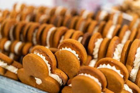 Making gingerbread man cookie sandwiches filled with eggnog buttercream, arrayed on a rustic wooden...