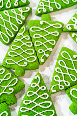 A detailed view of the white icing designs on green Christmas tree cookies, focusing on the...