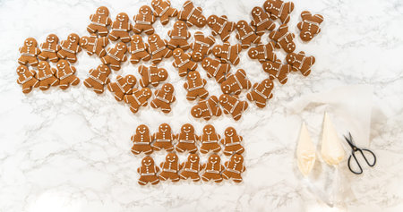 A festive arrangement of decorated gingerbread man cookies spread across a marble countertop, surrounded by holiday-themed baking tools, creating a cheerful and seasonal vibe.の写真素材