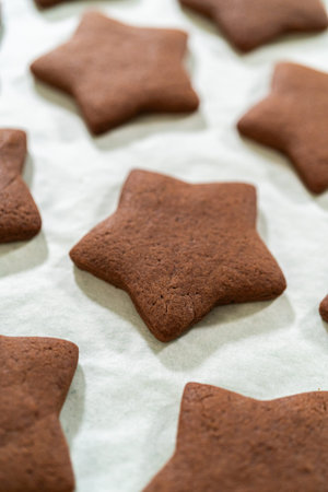Close-up overhead view of chocolate star cookies arranged closely on a parchment paper background.の写真素材