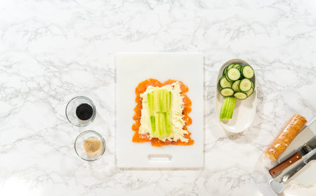 Cucumber ribbons are carefully placed on top of the cream cheese layer, completing the preparation...
