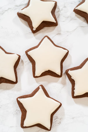 A neat arrangement of gingerbread star cookies covered in white royal icing, emphasizing their festive and uniform design.の写真素材