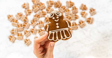 A close-up shot of a single decorated gingerbread girl cookie, held up to showcase its intricate royal icing dress details.の写真素材