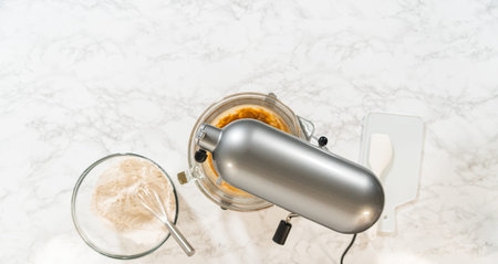 Overhead view of a stand mixer and prepared ingredients for Gingerbread Cookie Dough, ready for mixing. Dry and wet ingredients are arranged around the mixer on a marble surface.の写真素材