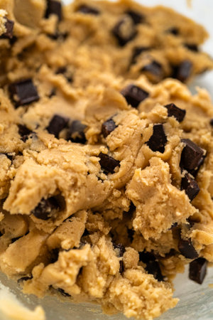 An extreme close up highlights chocolate chip cookie dough with rich texture. Lighting enhances the contrast between dough and chocolate.の写真素材