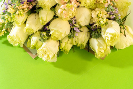 A lush arrangement of cream roses and pastel filler flowers with touches of purple is laid on a...