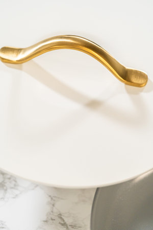 Top-down view highlighting a glossy gold handle on a white cookware lid. Excellent for modern cookware advertising, packaging, or ecommerce.の写真素材