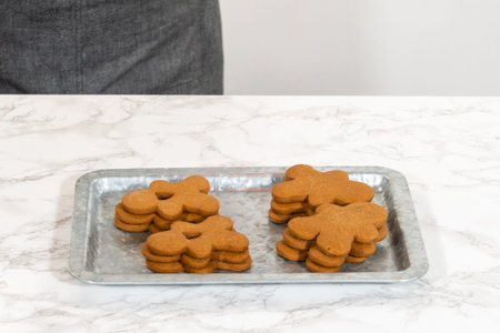 Gingerbread cookies, including a gingerbread man with a heart-shaped cutout, rest on a rustic metal...