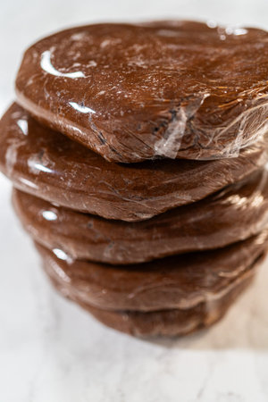 Multiple discs of Chocolate Gingerbread Cookie Dough wrapped in plastic wrap, stacked and ready to chill. These dough discs make it convenient to shape cookies for holiday baking.の写真素材