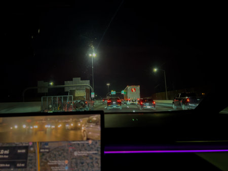 Denver, CO, USA-November 11, 2025 - A nighttime driving view shows a car approaching a parking lot...