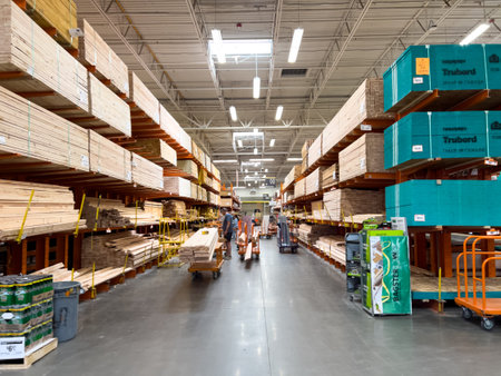 Parker, Colorado, USA-April 27, 2025 - An indoor view of Home Depot lumber section shows stacks of wood on tall shelves. Bright lighting and customers walking with carts are visible.