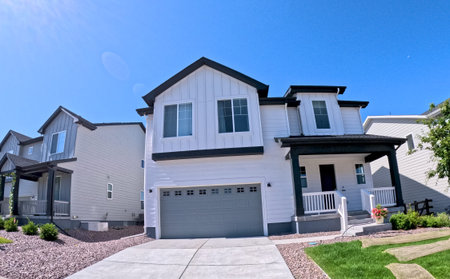 A close-up front view of a newly constructed two-story suburban house in Castle Rock, Colorado. The driveway, garage, and fresh landscaping are visible under a clear sky.
