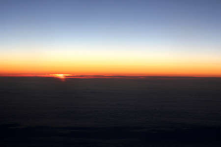 sunrise above the clouds from the plane windowの写真素材