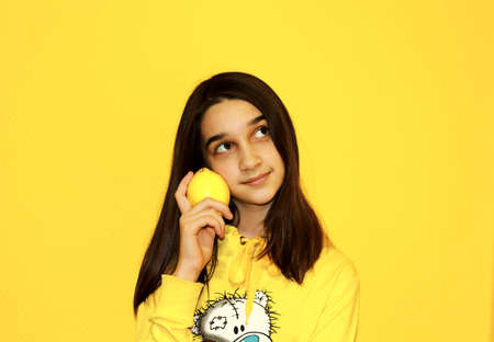 girl with lemon on a yellow backgroundの写真素材