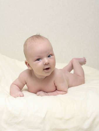 a small child lying on a yellow blanketの写真素材
