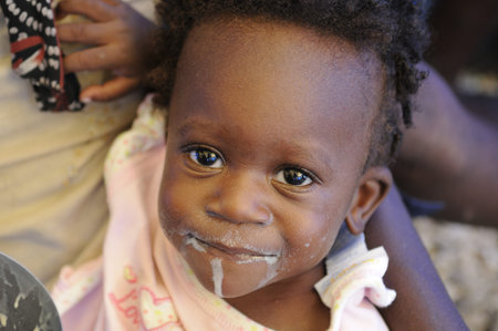 PORT-AU-PRINCE - AUGUST 28: An Haitian newsworthy kid smiling while eating her food in Port-Au-Prince, Haiti on August 28, 2010.のeditorial素材