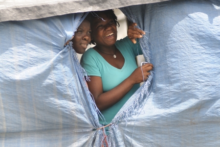 PORT-AU-PRINCE - SEPTEMBER 1:Camp residents peeping out through their tent window to watch a rally passing, in Port-Au-Prince, Haiti on September 1, 2010.のeditorial素材