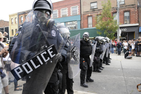 TORONTO-JUNE 26: Toronto Riot Police wearing gas masks restricting the protesters on Queen Street...