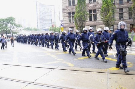 TORONTO-JUNE 26: Riot police group marching on the streets after a police car was torched nearby during the G20 Protest on June 26, 2010 in Toronto, Canada.のeditorial素材