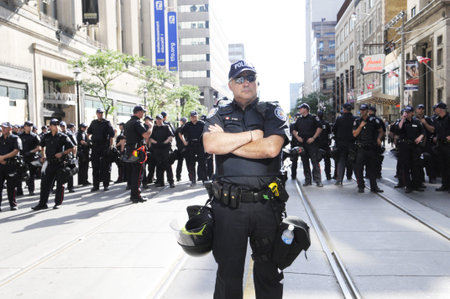 TORONTO-JUNE 28: A police officer keeping a close and careful eye on the people on the streets during the G20 Protest on June 28, 2010 in Toronto, Canada.のeditorial素材