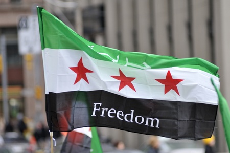 TORONTO-MARCH 16: A protester waiving a Syrian flag during a protest rally organized to raise awareness and commemorate two years of Syrian revolution on March 16, 2013 in Toronto, Canada.のeditorial素材