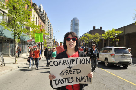 TORONTO-MAY 25: A teenage girl walking with a sign saying that GMO giant Monsanto is corrupt and greedy during a rally against GMO giant Monsanto on May 25, 2013 in Toronto, Canada.のeditorial素材