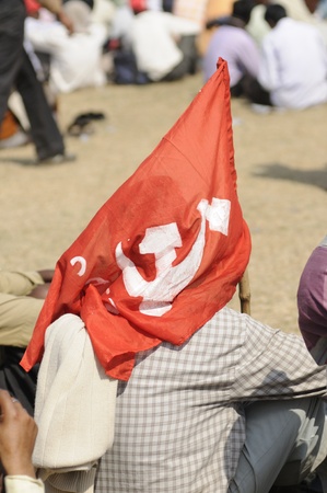 KOLKATA- FEBRUARY 13: An unidentified man covers himself up with the communist flag to escape the heat, during a political rally in Kolkata, India on February 13, 2011.のeditorial素材