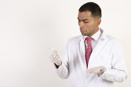 Doctor in a white coat and a pink tie being unappreciative about cigarettes on a white backgroundの写真素材