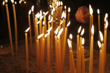 Woman lighting a candle  in a church for wishing healthy living