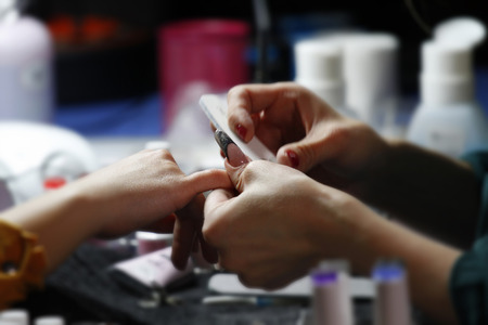 Nail manicure and polish in beauty salon in progressの写真素材
