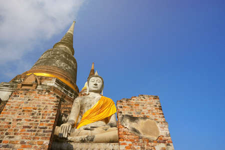 Travel Thailand - Buddha statue in Wat Yai Chaimongkol on blue sky and cloud background, Ayutthaya Historical Park. The brick pagoda at old ayutthaya temple ruins. Space for text in template.の写真素材