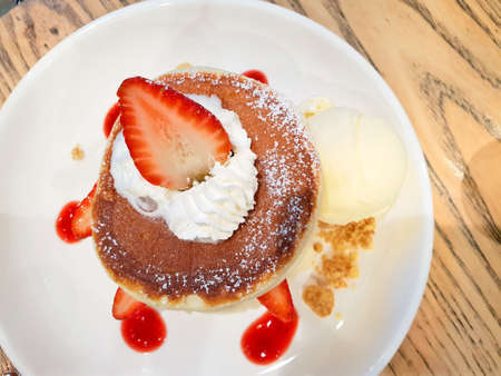 Top view strawberry pancakes with icing ,whipping cream and ice cream vanilla on wooden background.の写真素材